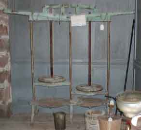 Large iron cheese press standing over 5 feet tall.